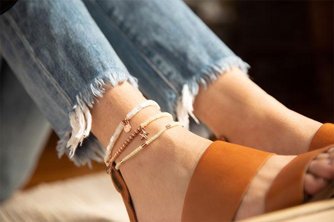 woman wearing a stack of summer anklets