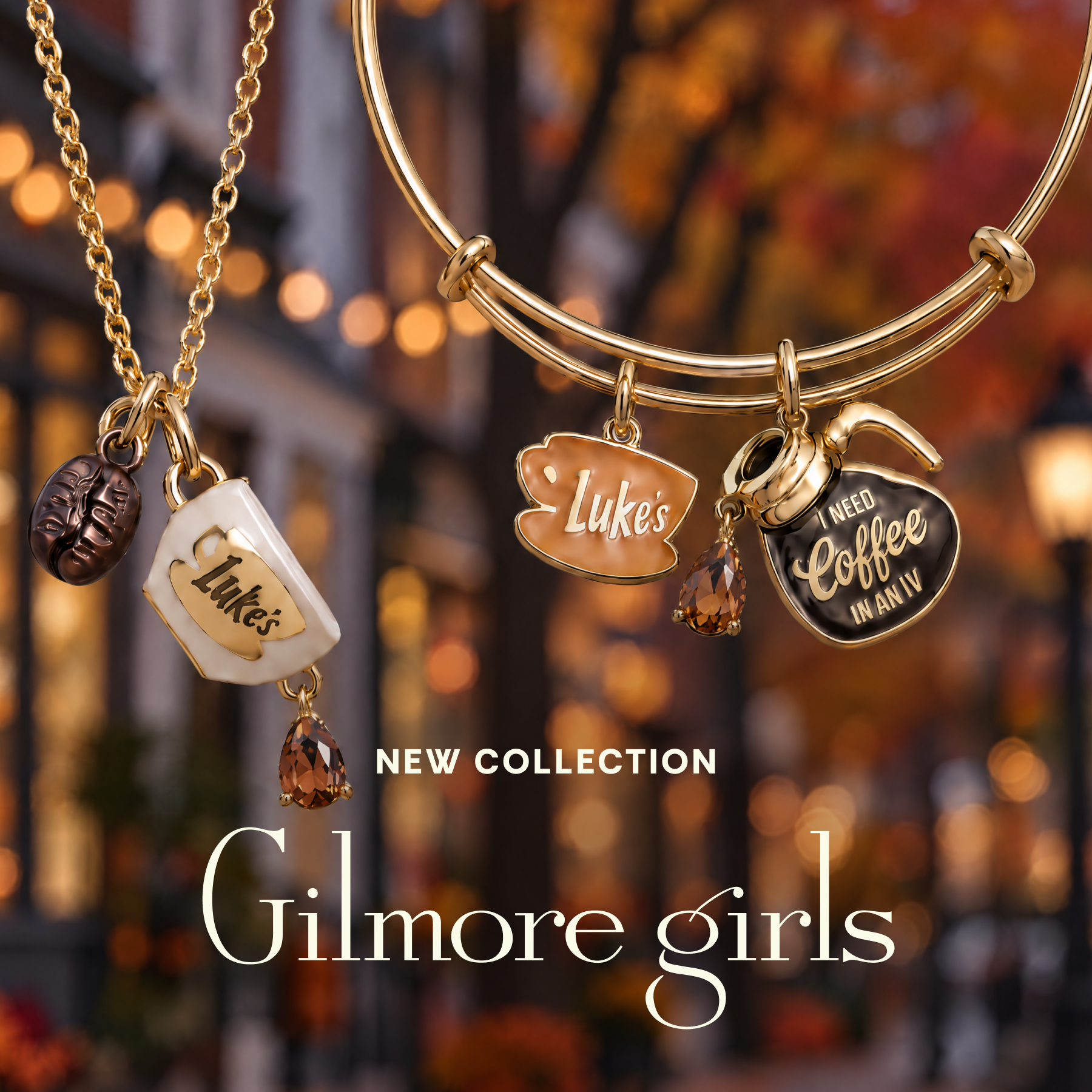 Gold-toned jewelry set with coffee-themed charms, including a necklace with a coffee cup charm and bangles with coffee cup and heart charms, shown against a blurred autumn street background with the text 'NEW COLLECTION' and 'Gilmore girls'.