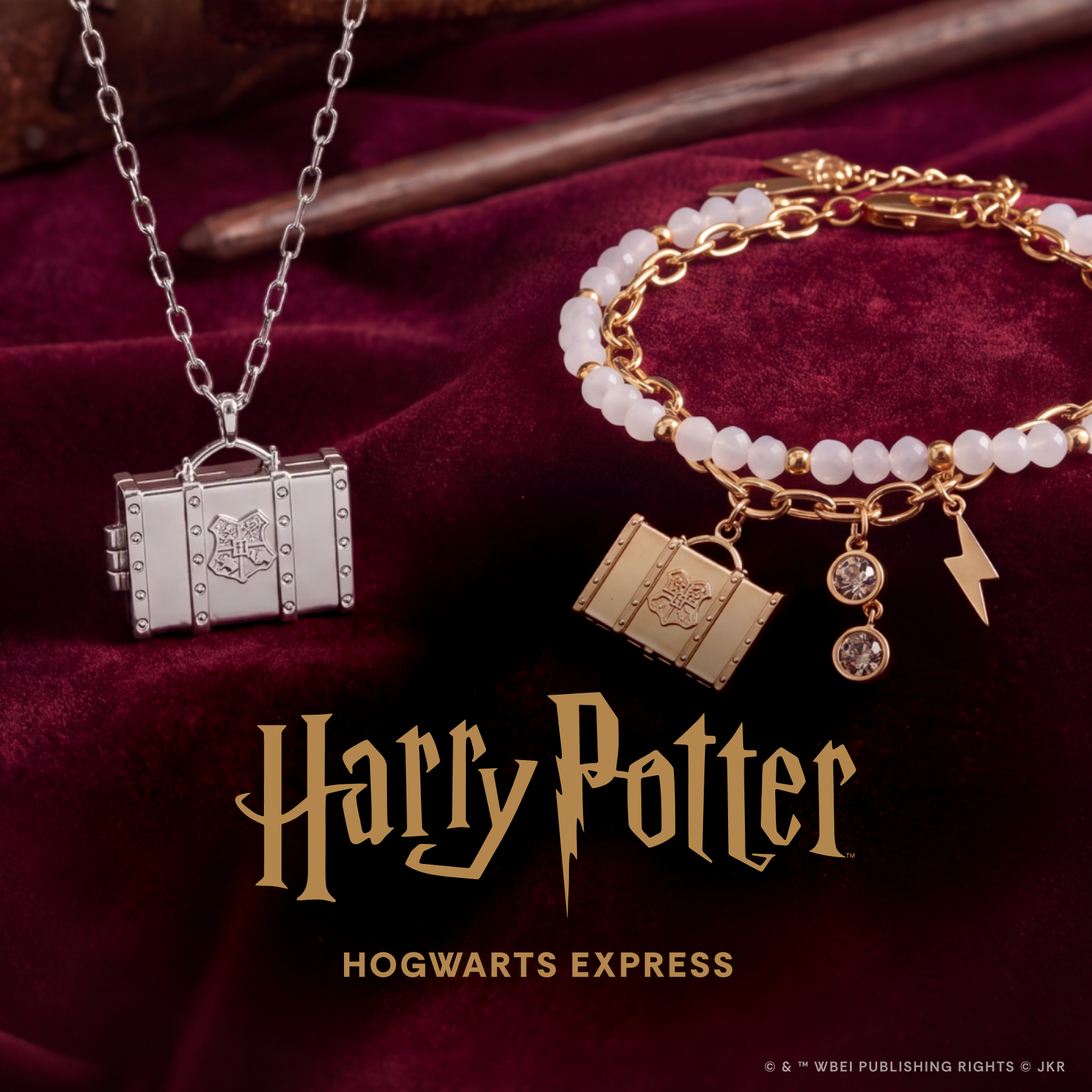 A Harry Potter Hogwarts Express jewelry set displayed on a deep burgundy velvet background. The set includes a silver-toned necklace with a miniature trunk pendant featuring the Hogwarts crest, a gold-toned bracelet with white beads, a book charm, a lightning bolt charm, and a crystal charm, and a gold-toned book-shaped pendant.