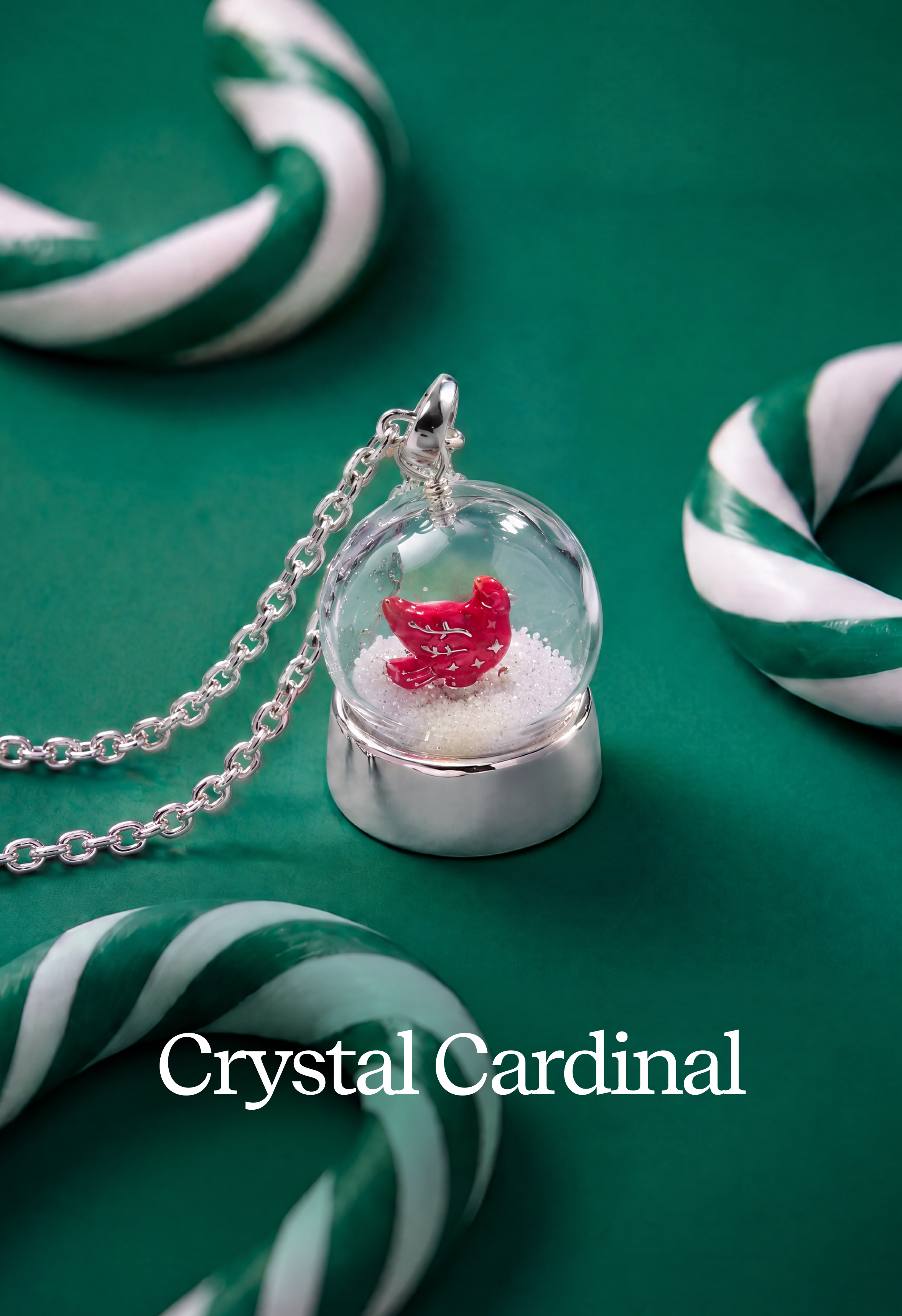 A silver chain necklace with a clear crystal dome pendant containing a small red cardinal and white glitter, styled on a green background with candy cane props. The text 'Crystal Cardinal' is overlaid at the bottom.