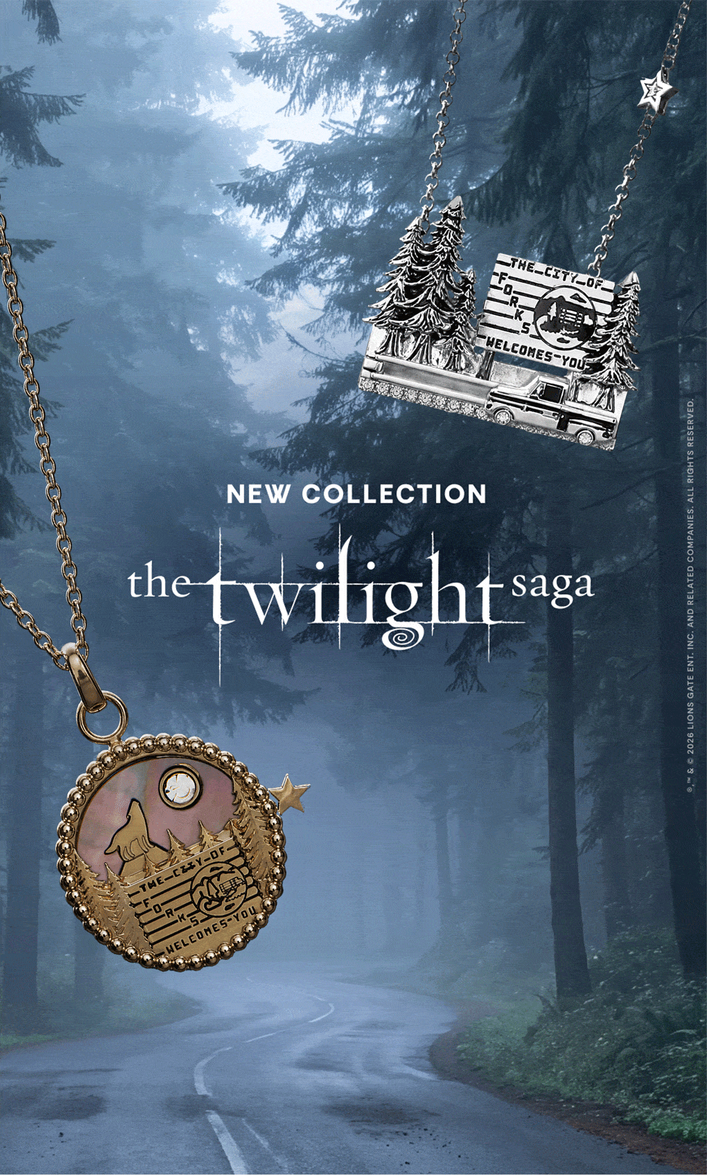 Promotional banner for 'The Twilight Saga' jewelry collection, featuring a silver pendant with a moon and stars design on the left and a bronze-toned pendant with a cabin and trees on the right, set against a misty forest road background 