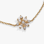 A gold chain necklace featuring a central snowflake-like pendant with clear baguette and round gemstones, photographed on a clean white background.