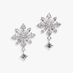 A pair of silver snowflake-shaped drop earrings with clear faceted crystals and small dangling star charms, shown on a clean white background.