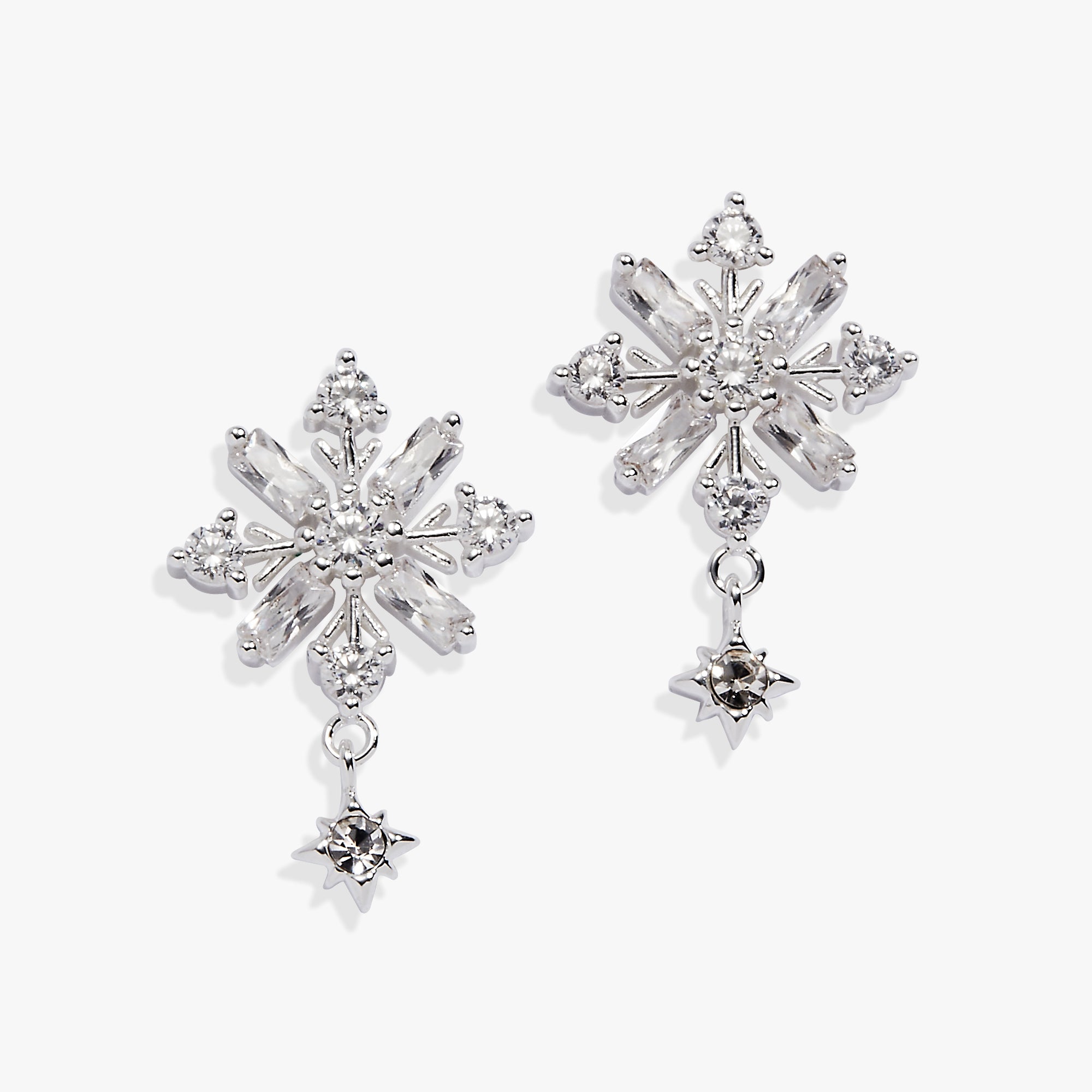 A pair of silver snowflake-shaped drop earrings with clear faceted crystals and small dangling star charms, shown on a clean white background.