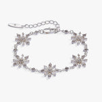 A silver-toned bracelet featuring five snowflake-shaped crystal clusters, a matching extender chain, and a lobster clasp, displayed on a clean white background.