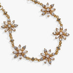A gold-toned necklace featuring five large starburst-shaped floral clusters set with clear baguette and round crystals, displayed on a clean white background.