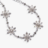 A silver-tone chain necklace featuring five large, clear faceted crystal snowflake motifs spaced along the chain, photographed on a clean white background.