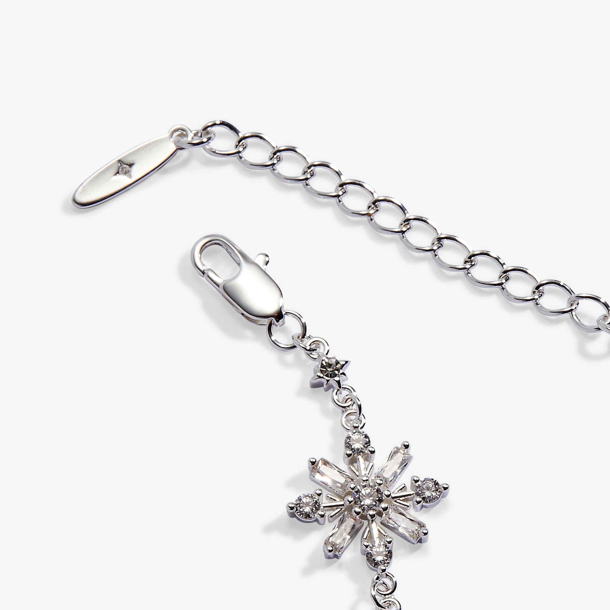Silver-tone chain extender with a lobster clasp and a dangling snowflake charm embellished with clear rhinestones, shown on a light gray background.