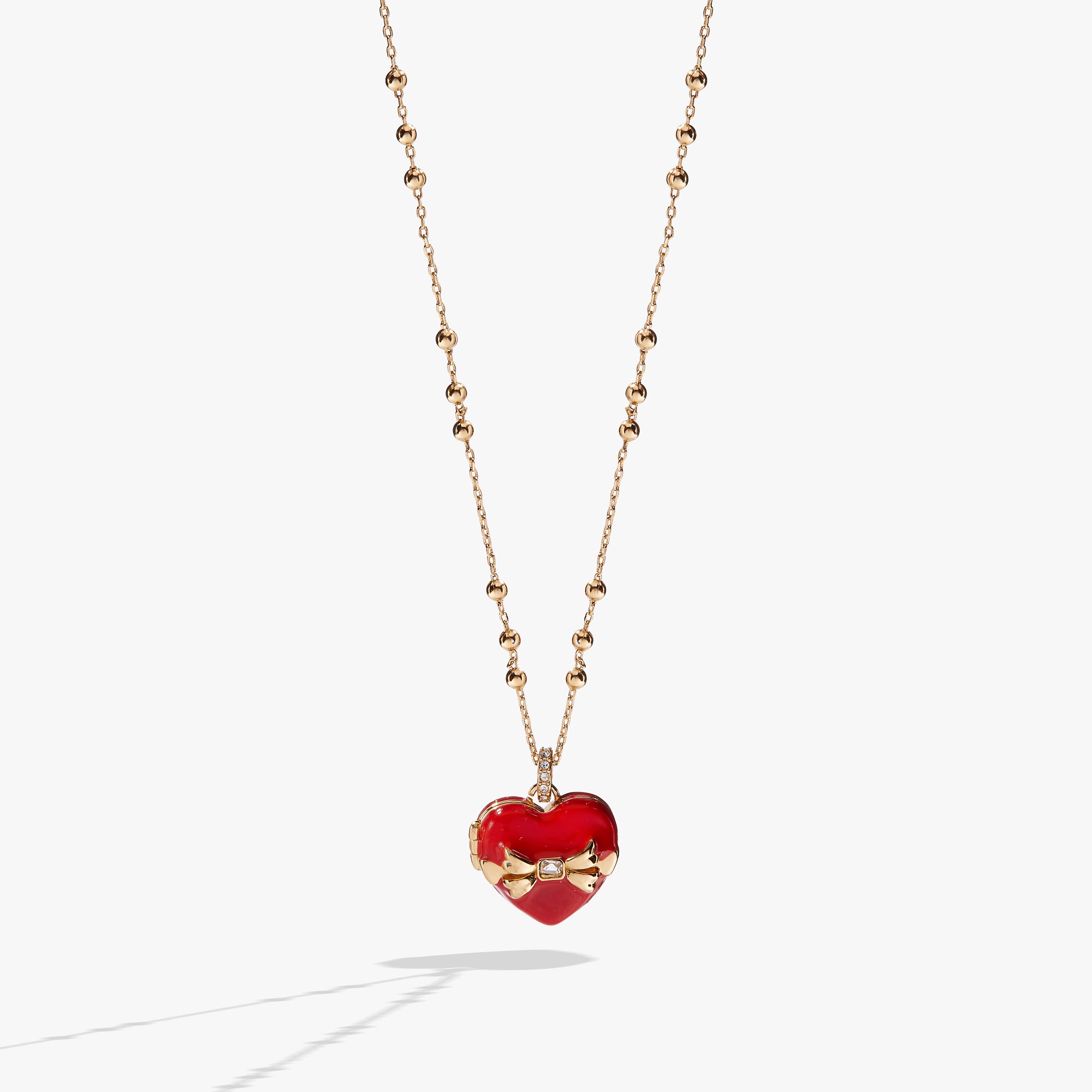 A gold necklace with a red and gold heart charm