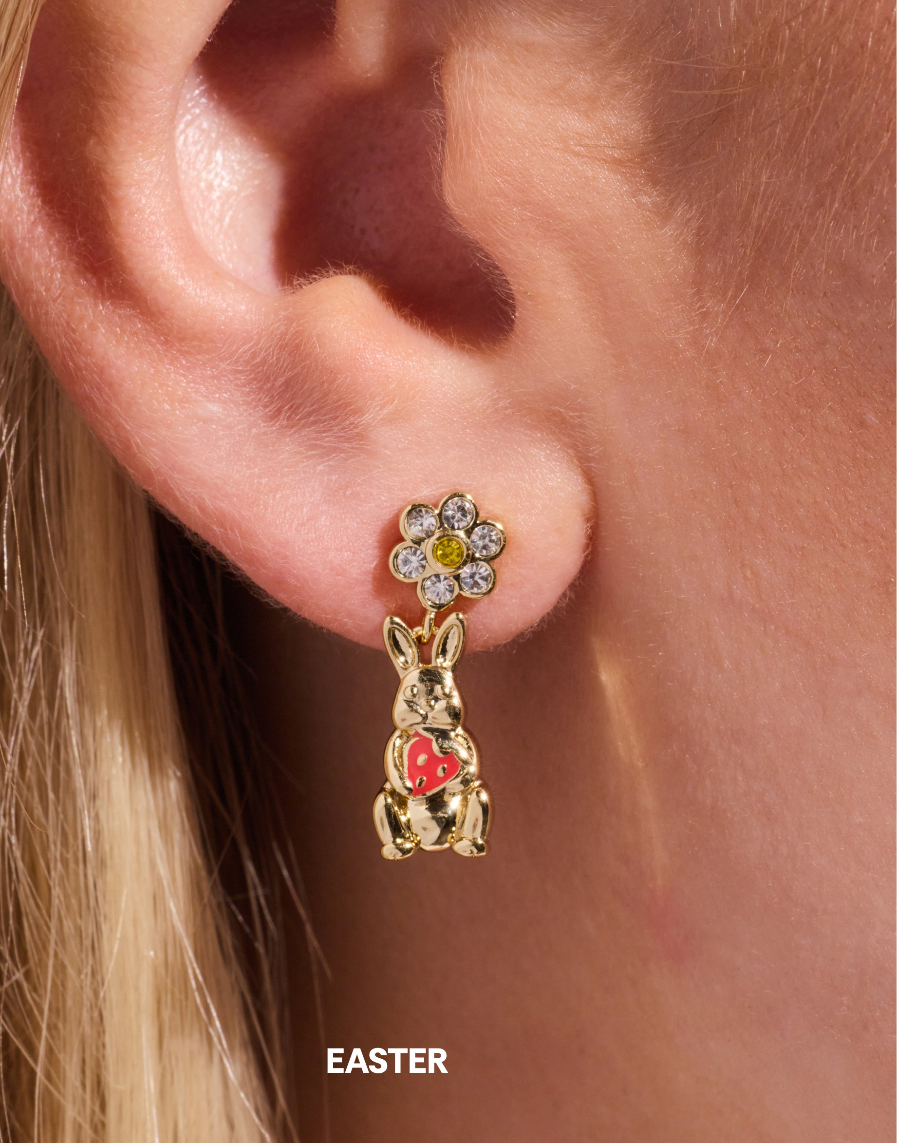 Gold bunny earring with a flower detail worn on an ear, labeled 'Easter'.
