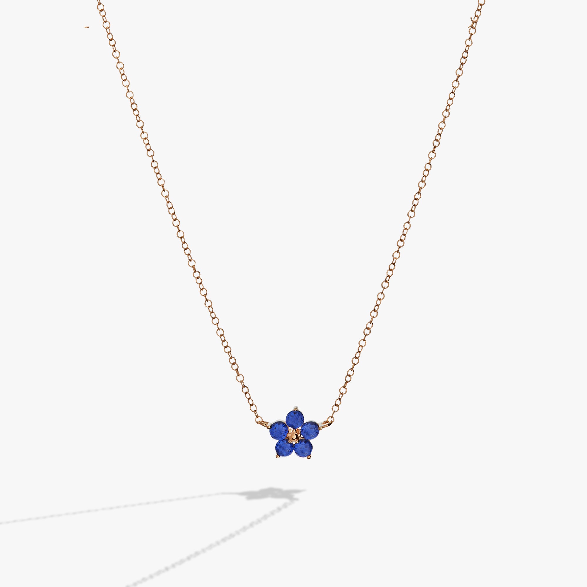 A gold necklace with a blue flower