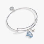 A silver bangle bracelet with a circular charm, a small star charm, and a light blue mitten charm, displayed on a clean white background.