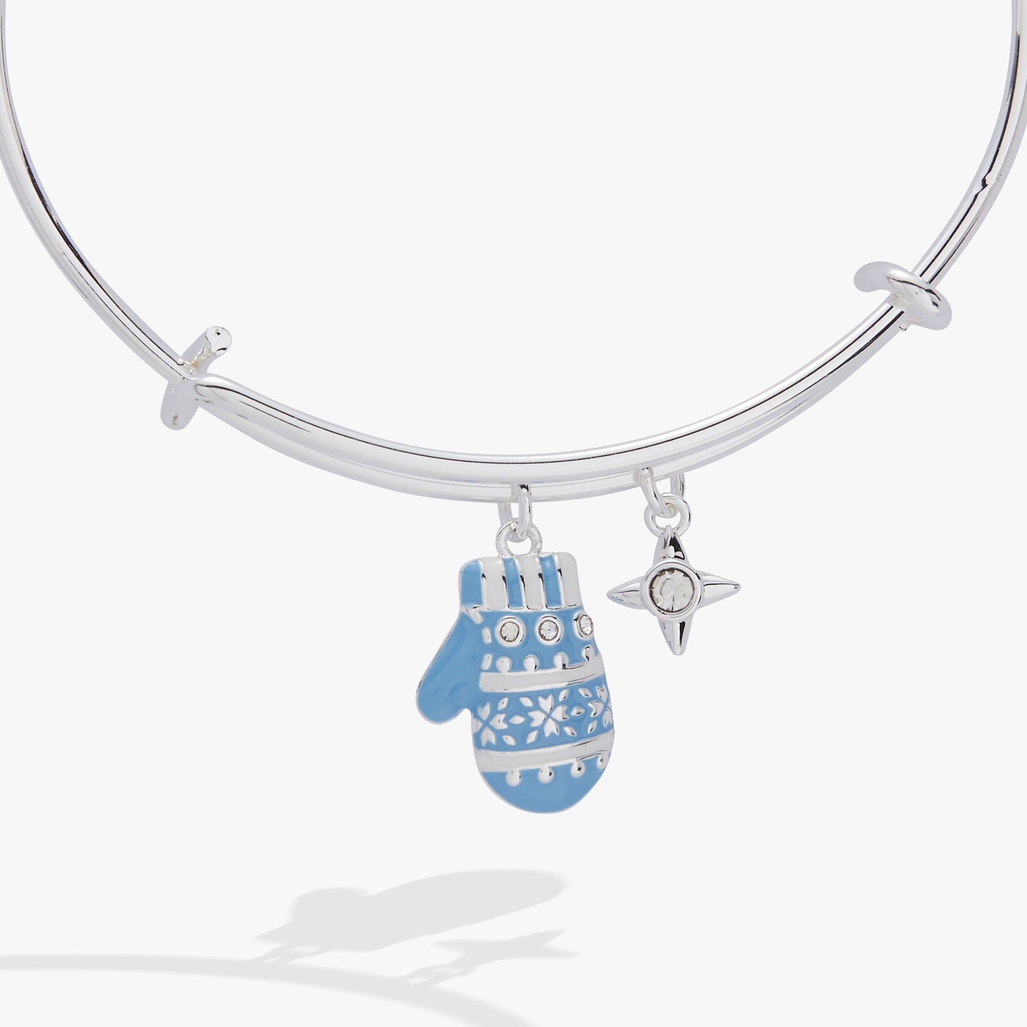 A silver bangle bracelet with a dangling blue and white patterned mitten charm and a small silver star charm, shown on a light gray background.