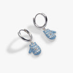A pair of silver huggie hoop earrings with dangling light blue mitten charms, shown on a clean white background.