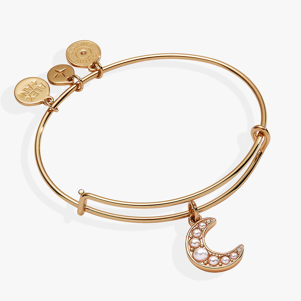 A gold bracelet with a pearl crescent moon charm on it
