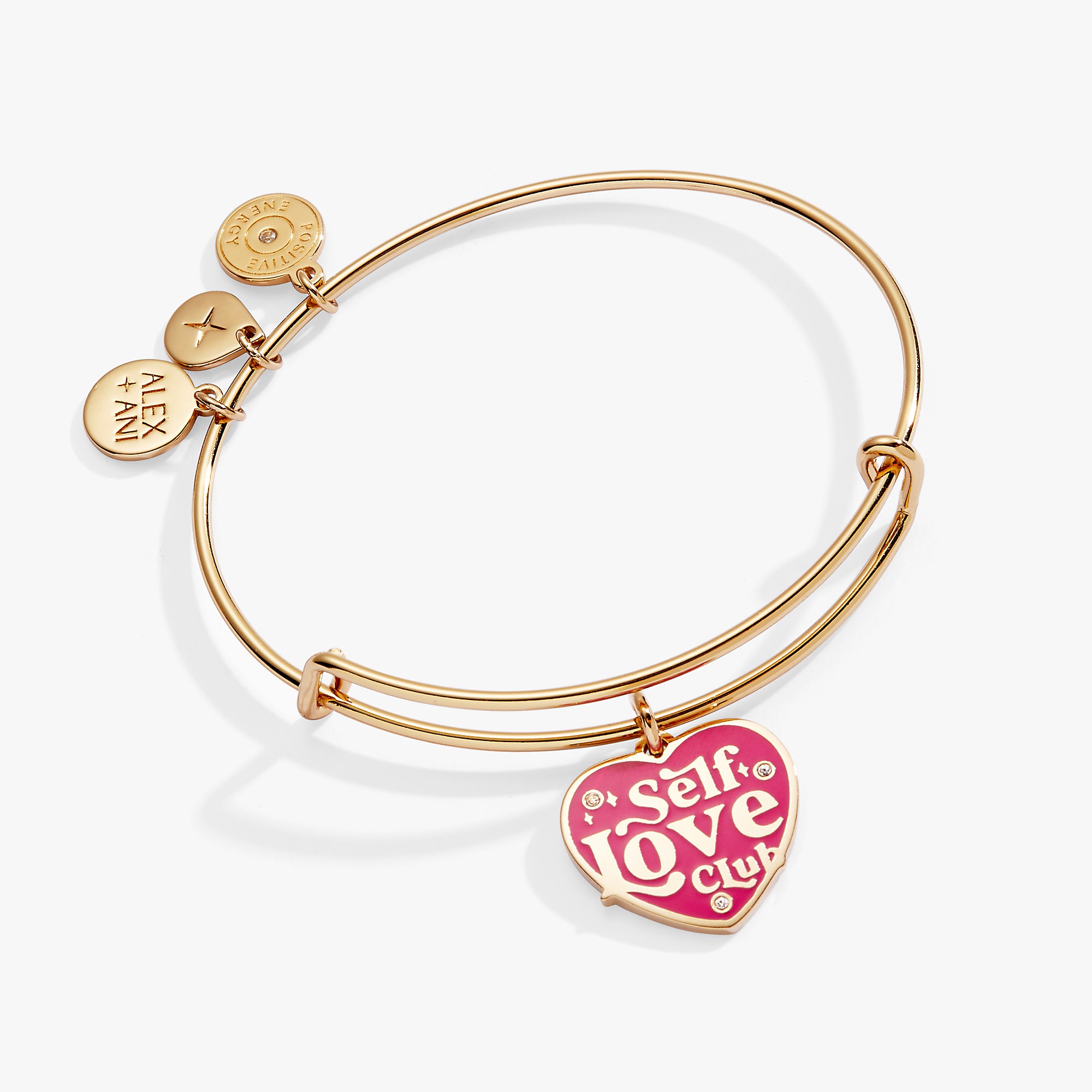 A gold bangle bracelet with a pink heart charm