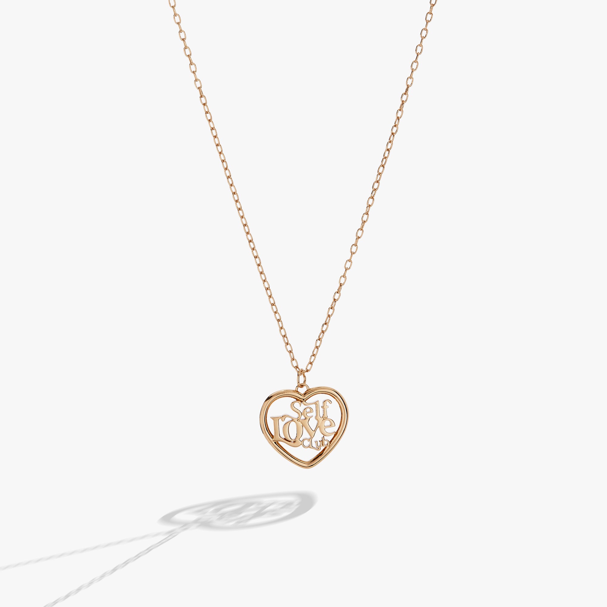 A gold necklace shaped like a heart with text inside