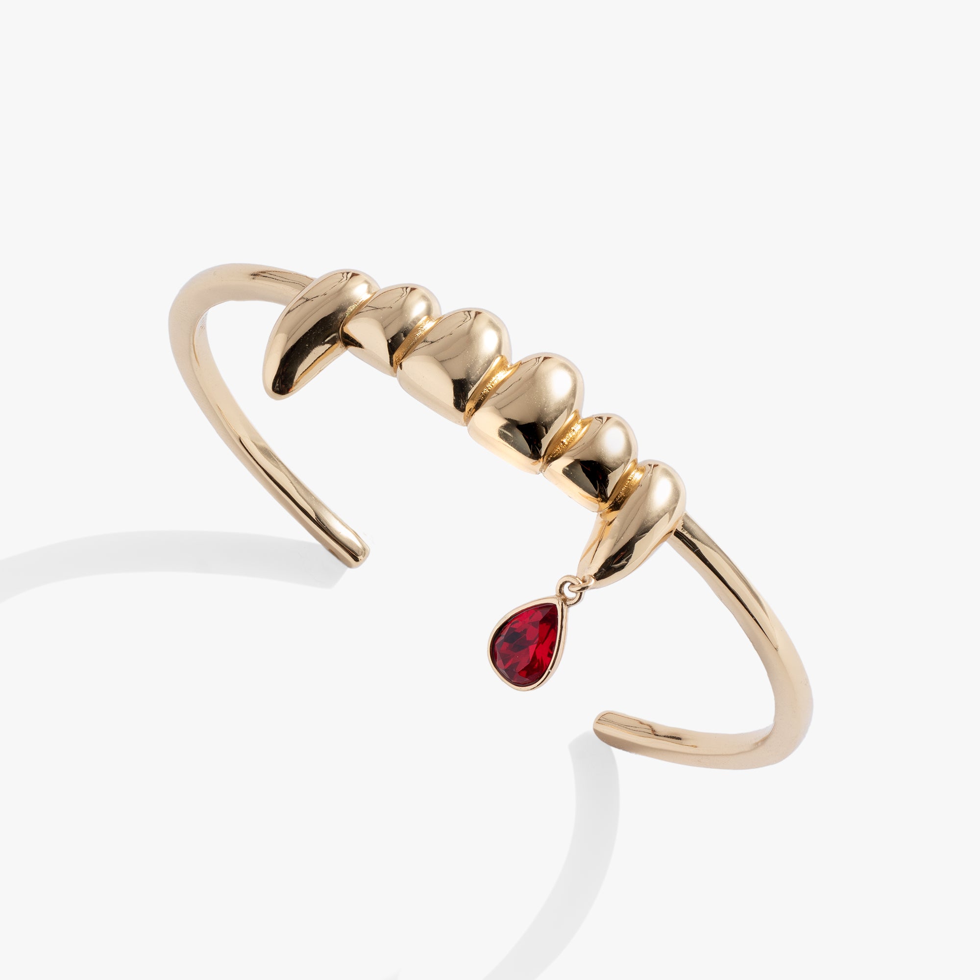  A gold bracelet with vampire fangs and a red gemstone